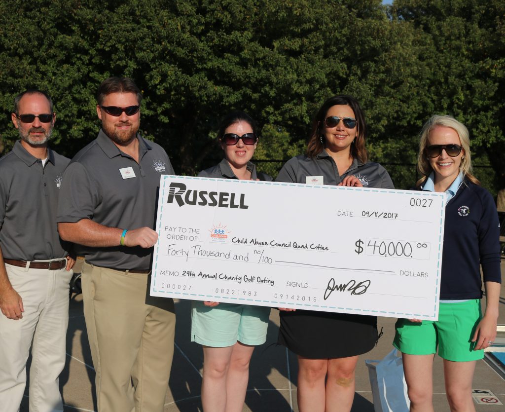 Five Russell employees standing in front of a giant check made out to charity.
