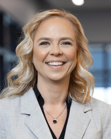 Portrait photo of blonde middle-aged woman in gray suite.