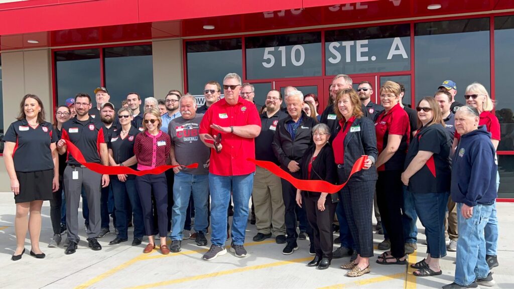 Team of I-80 truck stop employees cutting a ribbon in front of their newly renovated building.