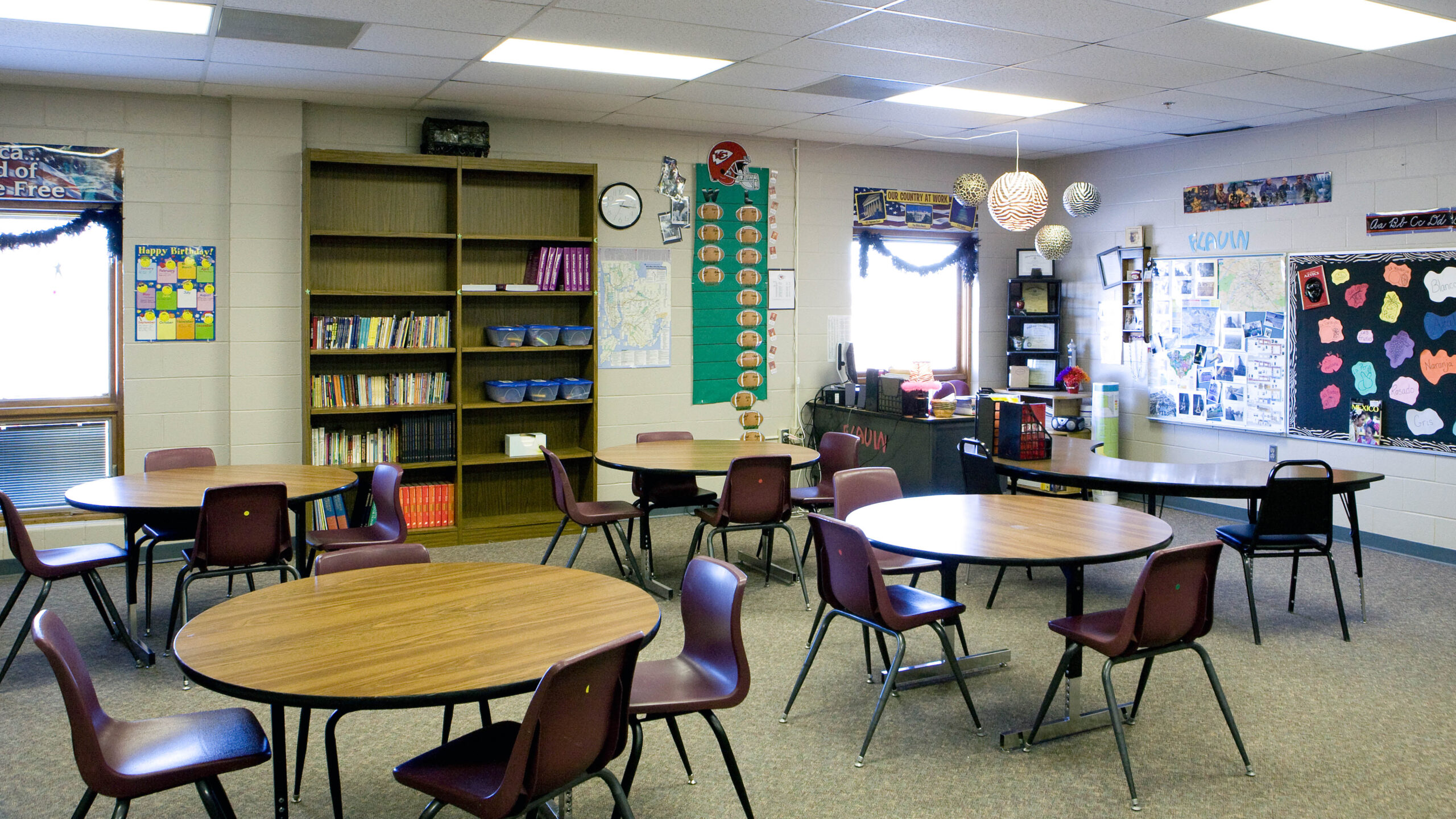 classroom with round tables, chairs, and shelving
