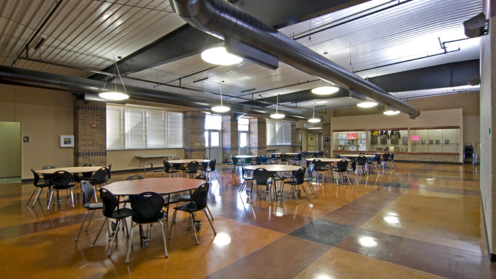 cafeteria with rounded tables, chairs, and trophy case