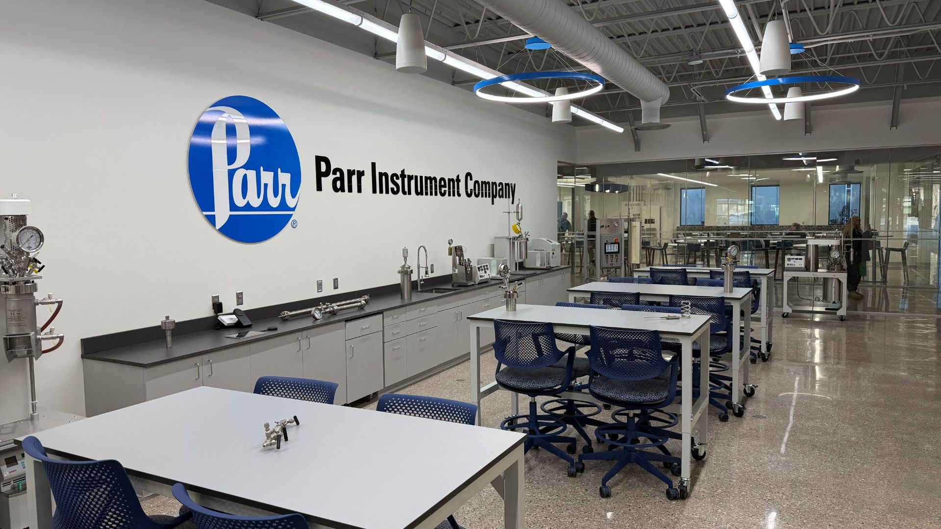 Demonstration lab at Parr Instrument Company with a wall logo, work tables, and pressure reactors on lab benches.