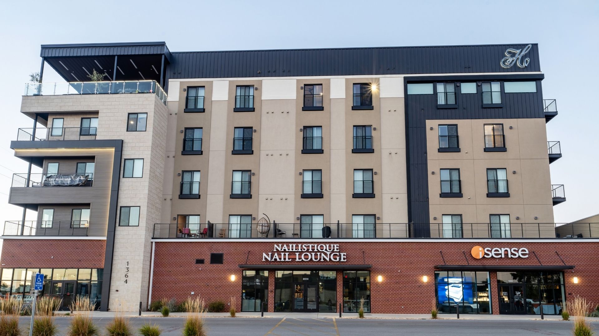 Front exterior of Heritage Flats in Springfield, Missouri, with a brick retail base, five stories of apartments and a rooftop terrace