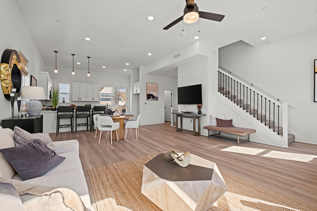Open-concept townhome interior at Village at New Longview with living area, kitchen bar seating, and staircase