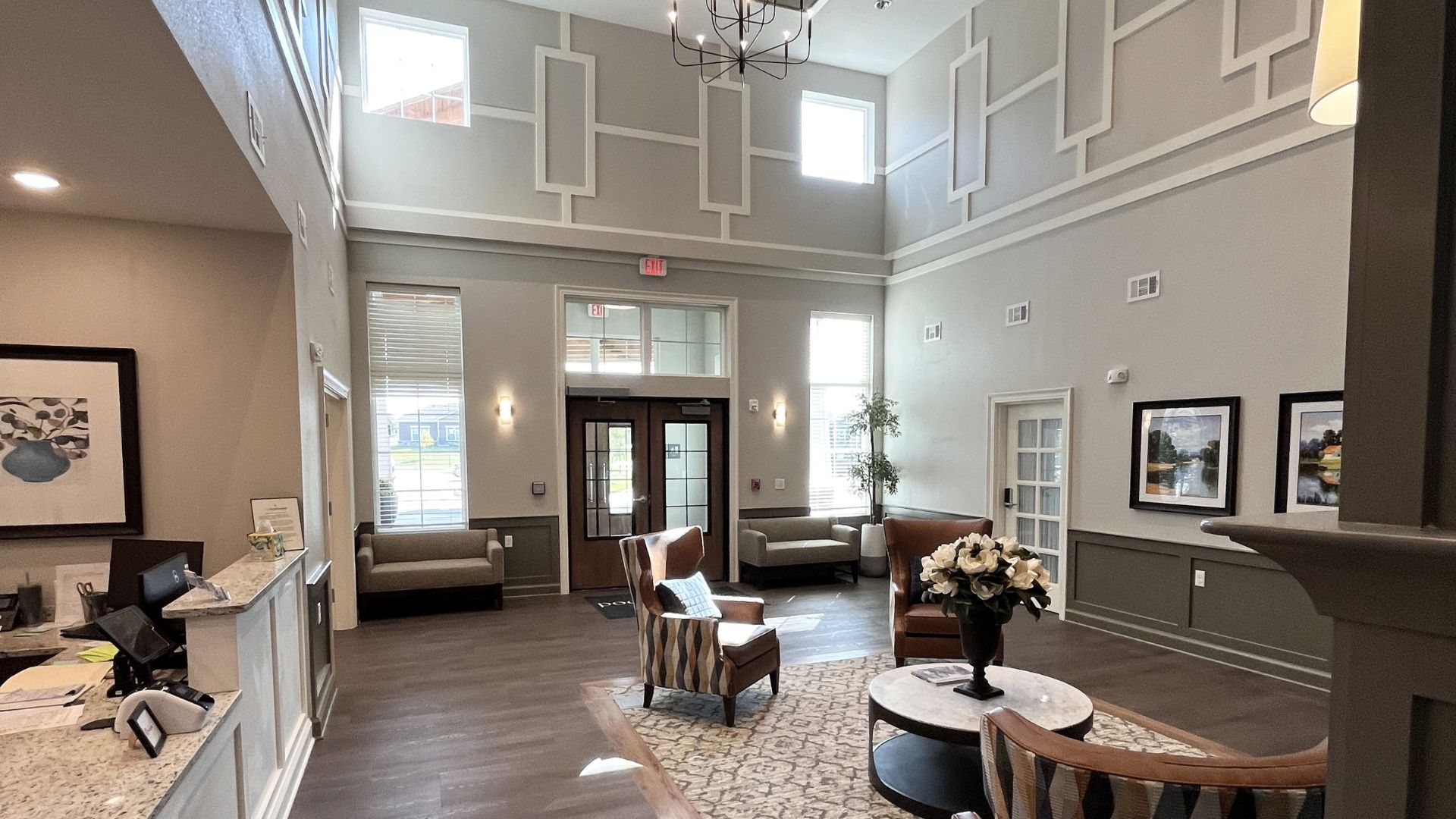 Two-story lobby at The Rushwood Senior Living in Wichita, Kansas, with a reception desk, wingback chairs, and clerestory windows