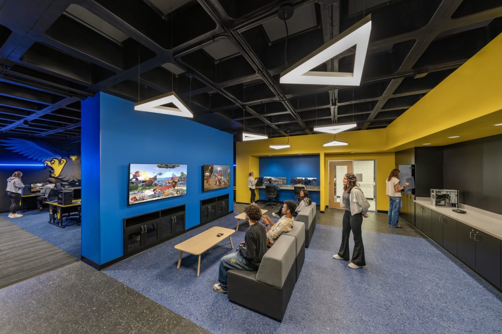 Students gather in the e-sports lounge and gaming lab at Black Hawk College Building 2 with blue and gold walls