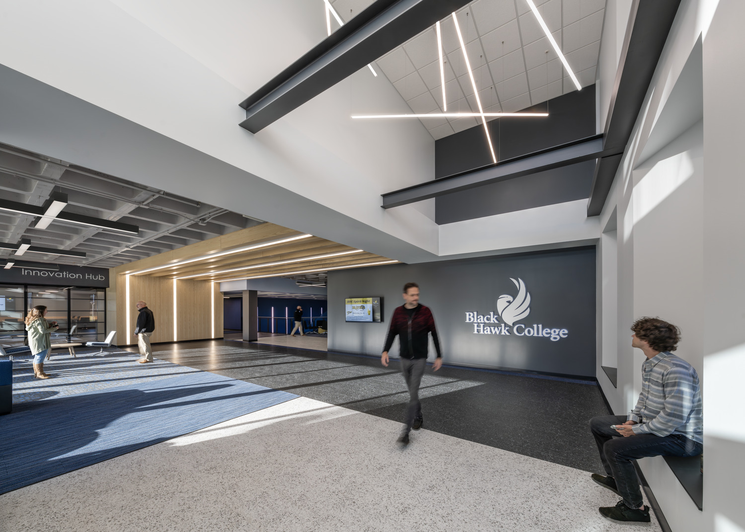 High-ceiling lobby inside Black Hawk College Building 2 with exposed steel beams, linear lighting, and the Innovation Hub