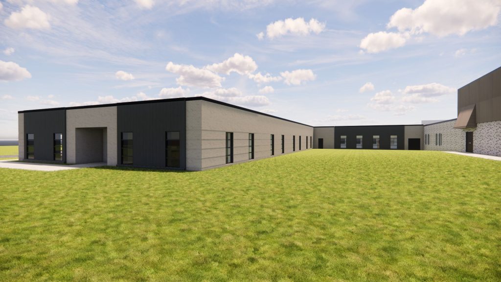 Exterior view of Bettendorf Middle School addition with beige brick and dark metal panel facade and adjacent grass field