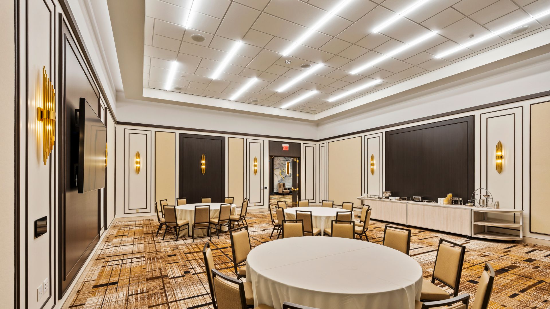 Meeting room with round tables, gold wall sconces, and catering station