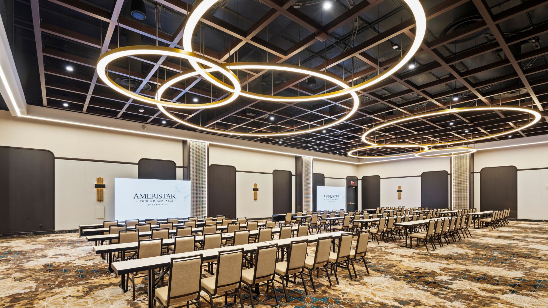 Ballroom set classroom style with rows of tables under circular gold pendant lighting