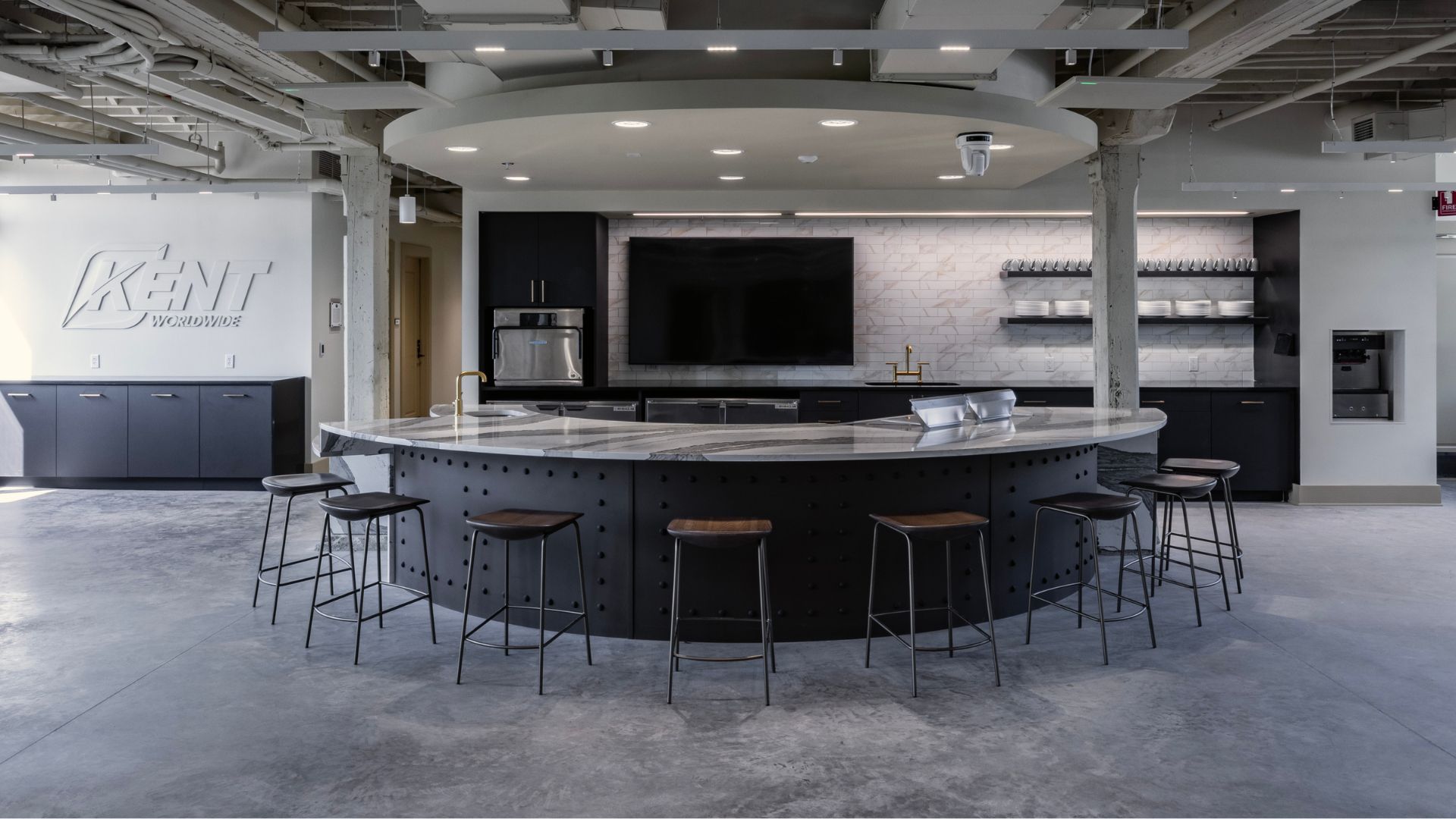 McKee Building breakroom with curved marble bar, stools, and Kent Worldwide signage