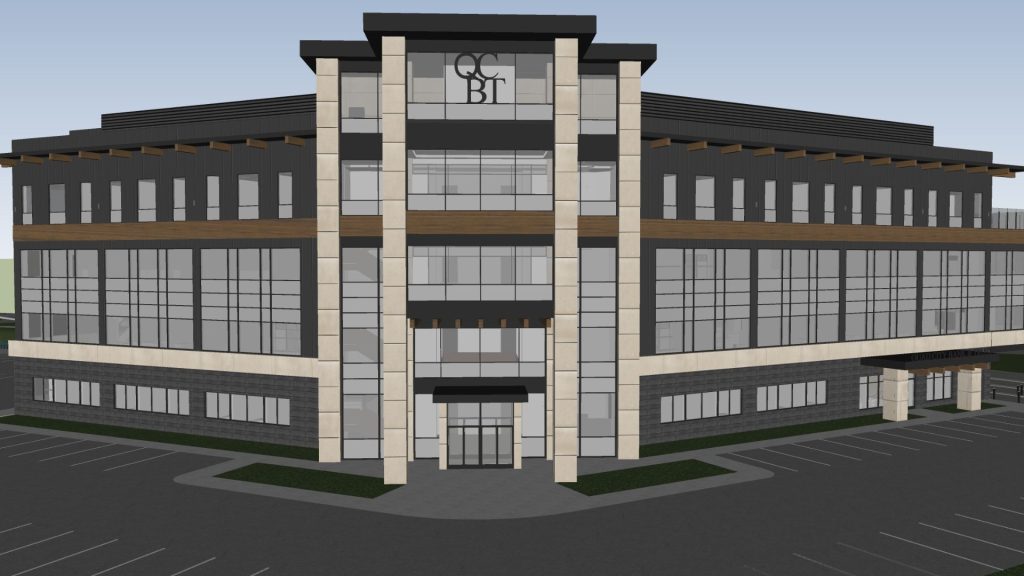 Architectural rendering of QCR Holdings/Quad City Bank & Trust headquarters in Bettendorf, Iowa, showing the glass-fronted corner entrance with stone pillars, QCBT signage, and a covered walkway to the parking lot.