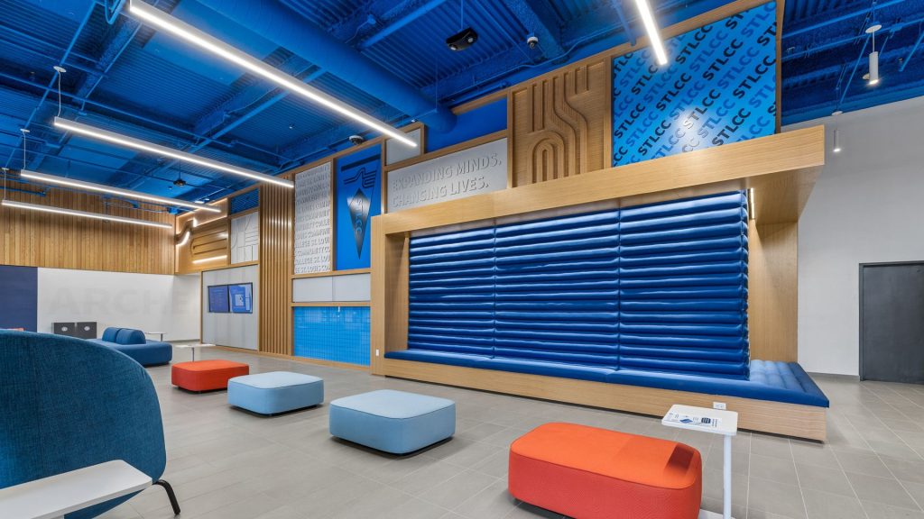 STLCC Meramec Student Center lounge with blue upholstered seating wall and wood accent branding display