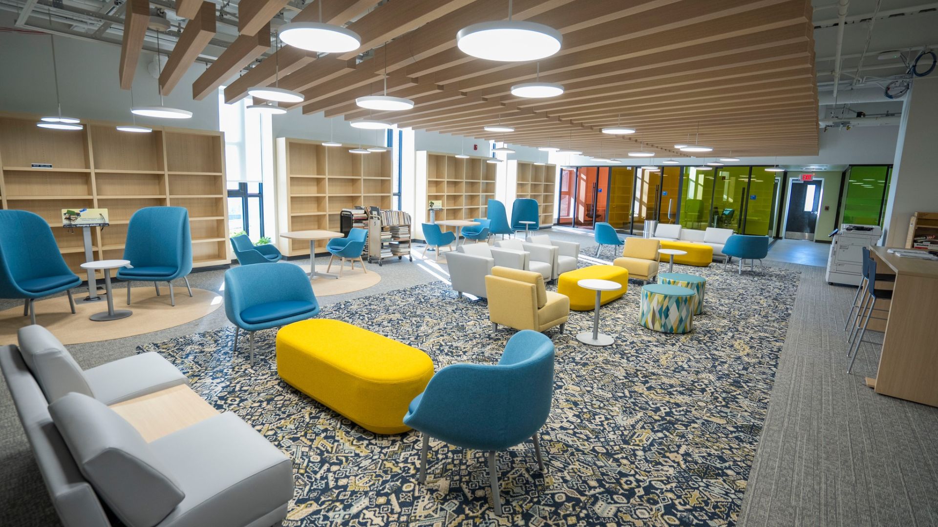 STLCC Florissant Valley library lounge with colorful seating, bookshelves, and wood slat ceiling