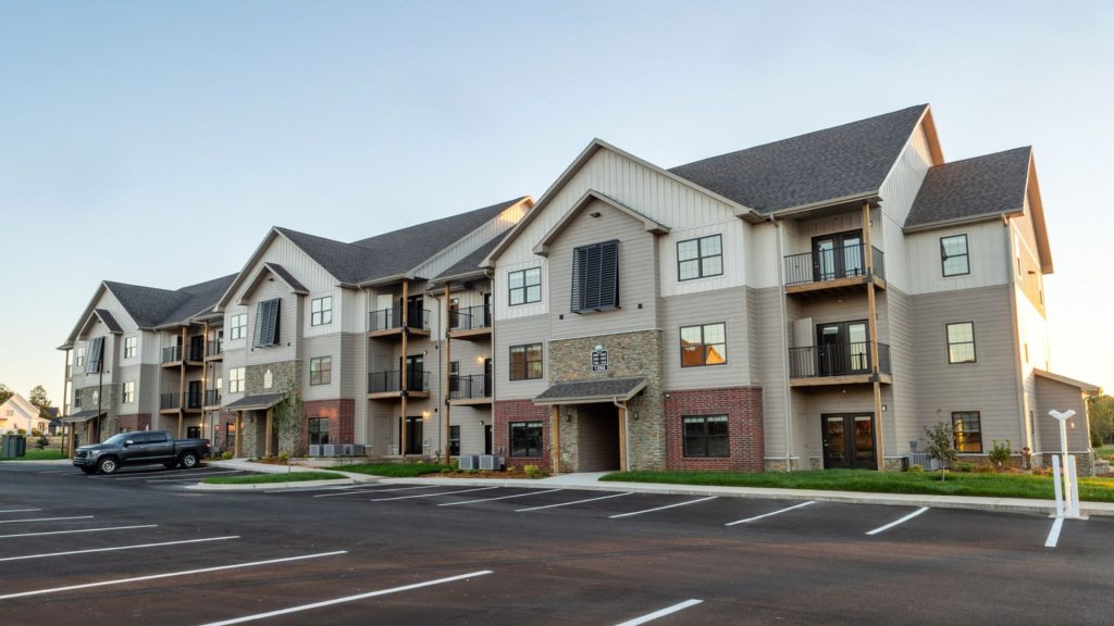 Three-story wood-framed apartment building with stone, brick, and siding exterior at The Meadows at Wicklow in Nixa, MO