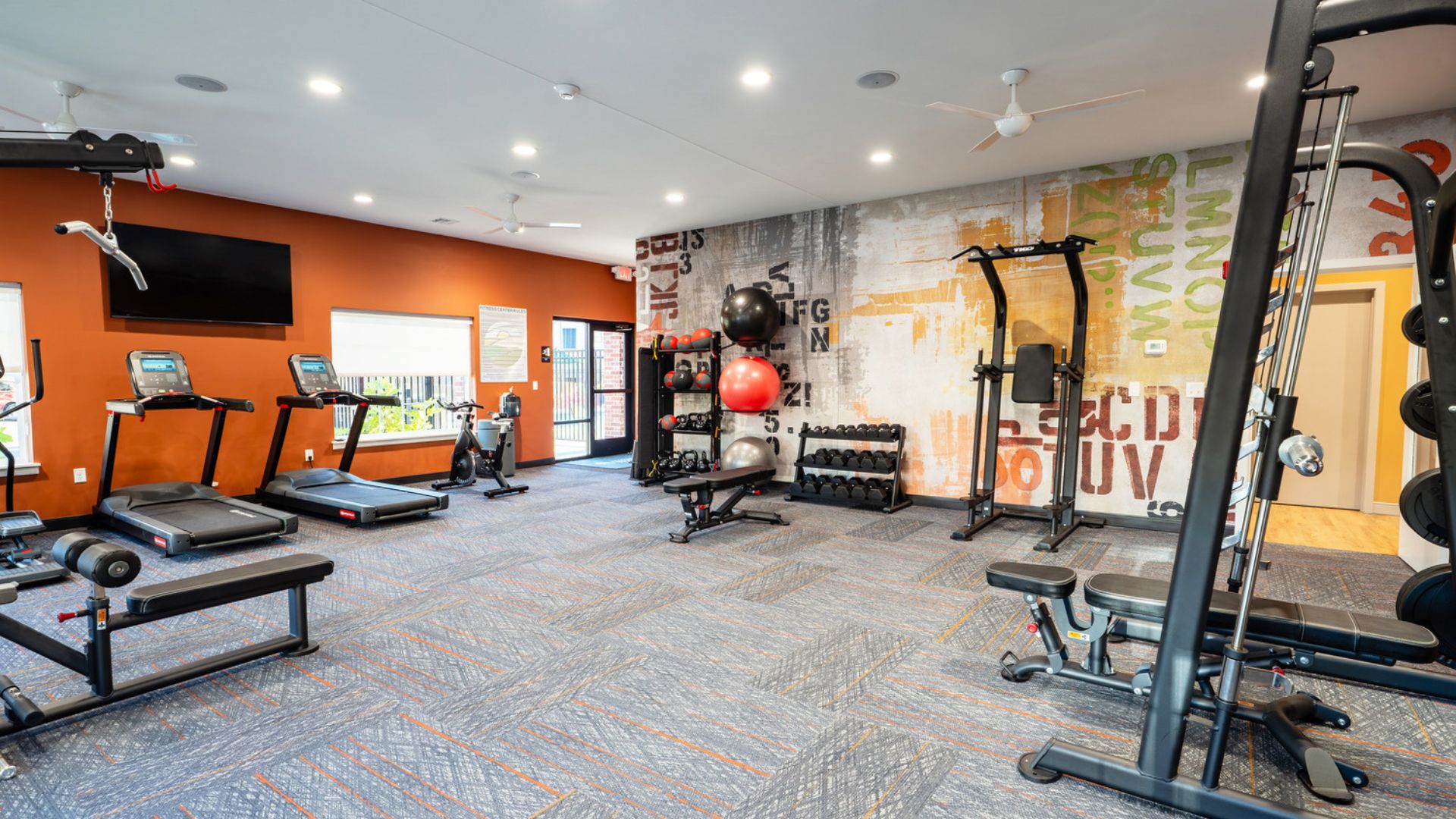 Fitness center with treadmills, free weights, and accent walls at The Meadows at Wicklow in Nixa, MO