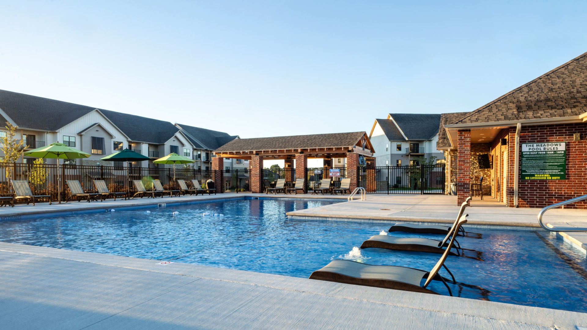 Resort-style swimming pool with in-water lounge chairs and outdoor pavilion at The Meadows at Wicklow in Nixa, MO